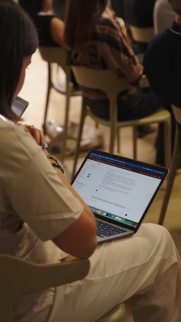 Résztvevő laptopon jegyzetel az AI Egyetem élő eseményén, háttérben a közönség ül.